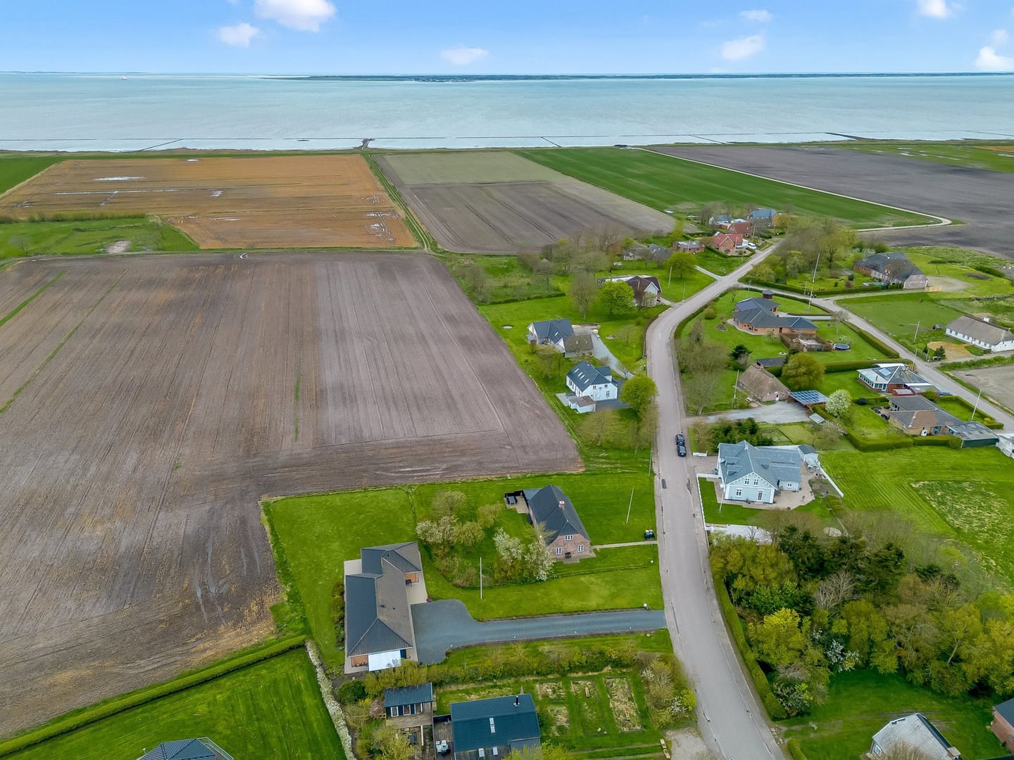 Aerial view of the marsh and fields meeting the Wadden Sea, with scattered farmhouses along a country road.