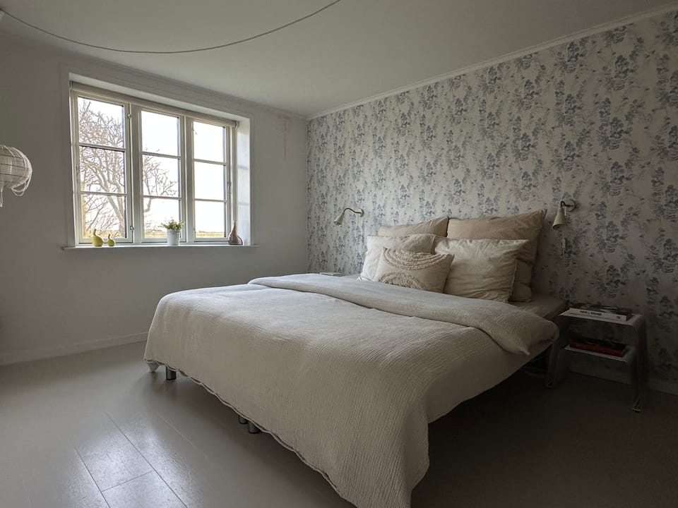 The ground-floor bedroom with a double bed, soft floral wallpaper and a marsh view.