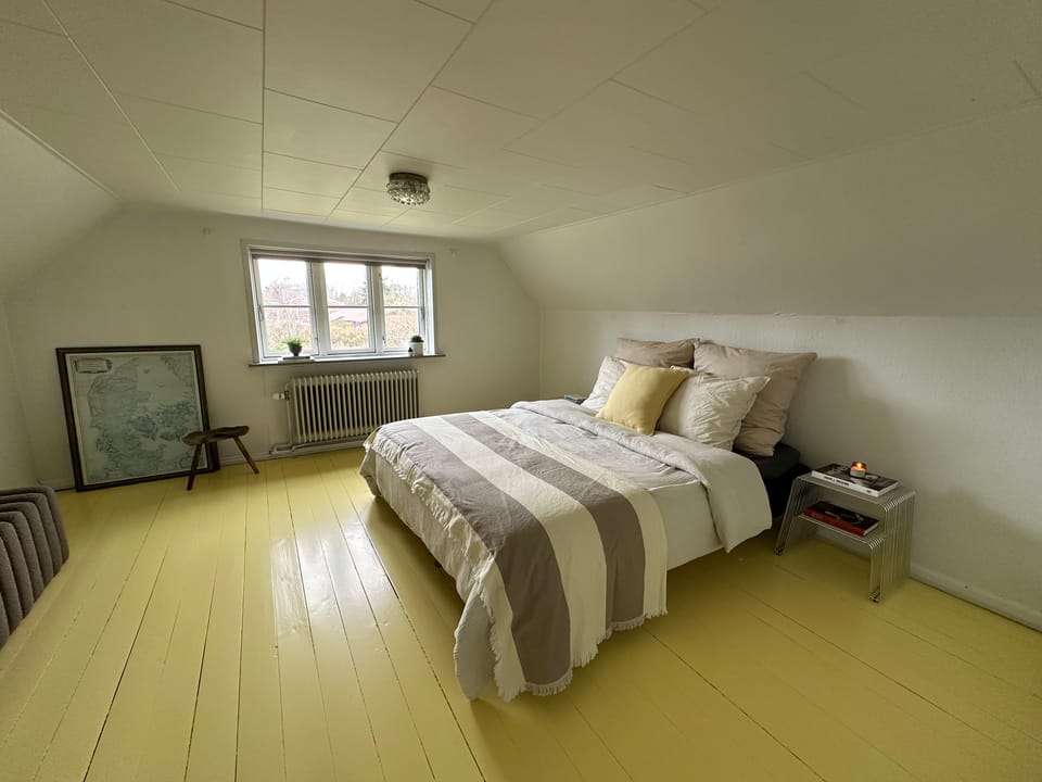 The main bedroom under the eaves, with a double bed and painted floorboards.
