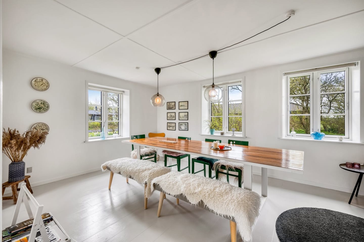 The dining room, with a long wooden table, green chairs and a wood-burning stove.