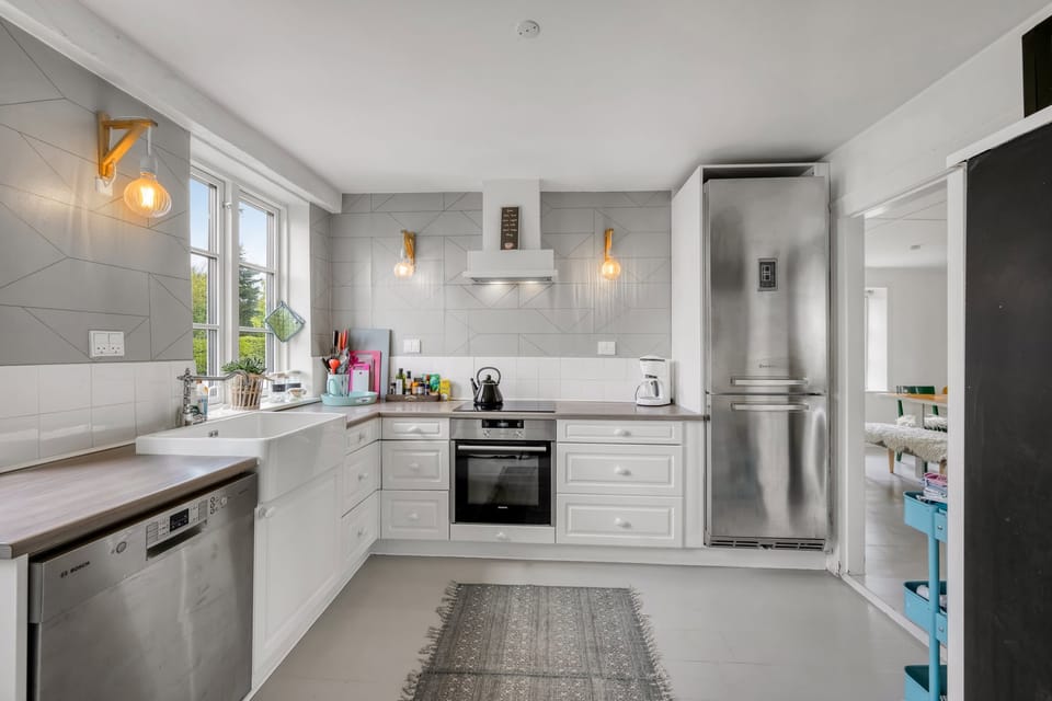 The kitchen with white cabinets, a farmhouse sink and a window over the counter.